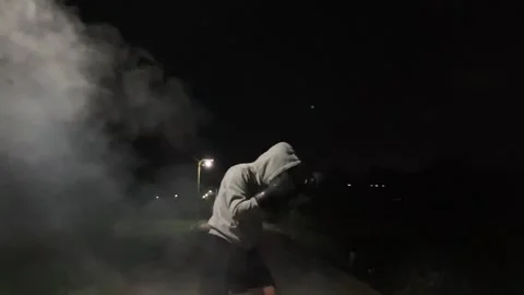 A hooded man practicing shadow boxing in smoke under a street light at night Stock Footage 340196140