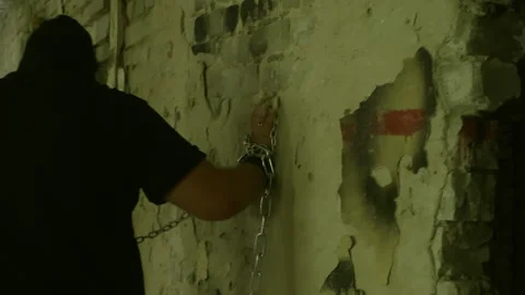 Hooded man pulling chain attached to ruined wall Stock Footage 304944049