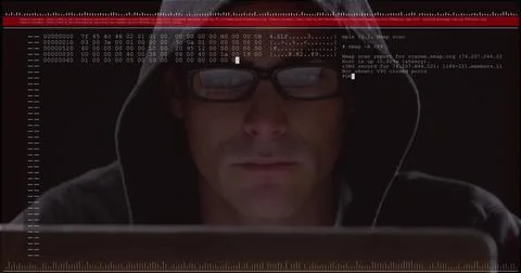 Hooded man scanning network data in dim room, with laptop hex dump overlay and Stock Photos
