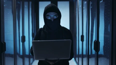 Hooded professional hacker programming code on laptop, deactivating data center Stock Footage 120695760