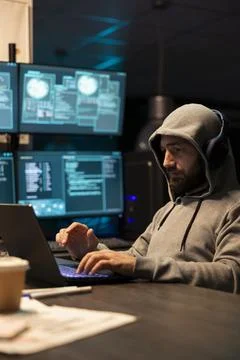 Hooded programmer writing coding scripts for catching fraud and scammers Stock-Fotos