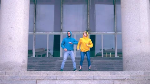 Hooded young couple performs synchronized steps in funky style 스톡 동영상 154834072