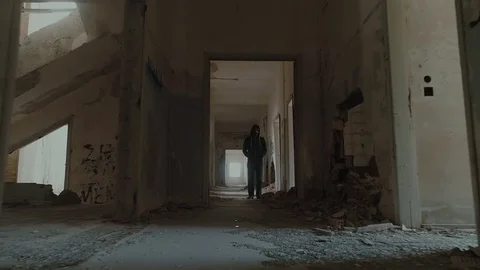 Hooded young man inside destroyed building,slow motion,dramatic drone shot Stock Footage 80069703