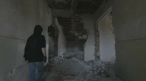 Hooded young man walking through the hallway of an abandoned building Vidéo 60702951