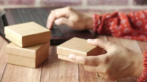 Hooding cardboard parcels while typing on laptop 库存影片 168006658