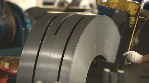 Hook the coil for the tap with your hands and raise. steel coils lie side by Stock Footage 94971743