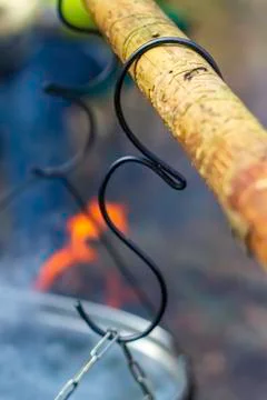 The hook for hanging the boiler on a fire hangs on a stick. Vertical. Stock Photos