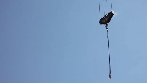 Hook of a lifting crane staggers in the air against a clear blue sky. Detail of  Stock-Footage 131056971