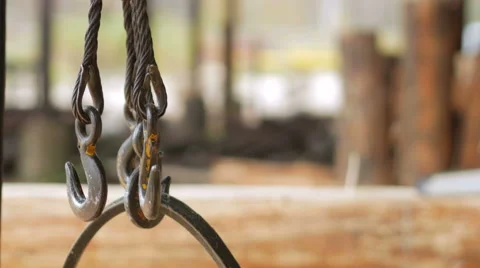 Hook of Overhead Winch Crane close-up. Builder sawing wood using a chainsaw in Video stock 69069019