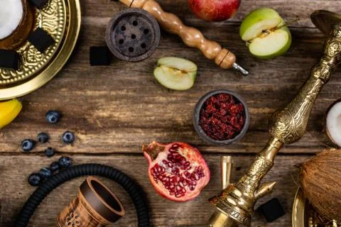 Hookah components on a rustik old wood table with fruits, tobacco and cocoa c Stock Photos
