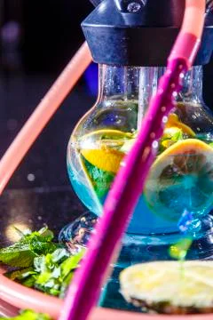 The hookah flask is round and transparent, filled with blue liquor. Sliced or Stock Photos