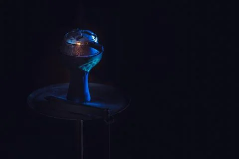 The hookah stands on a dark background with cold blue lighting. Stock Photos