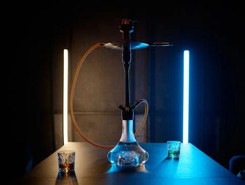 Hookah on table with glasses filled brandy in neon light Stock Photos