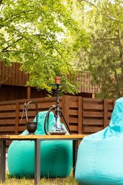 Hookah on a table in a park with soft chairs and green foliage, outdoor rec.. Stock Photos