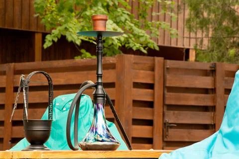 Hookah on a table in a park with soft chairs and green foliage, outdoor rec.. Stock Photos