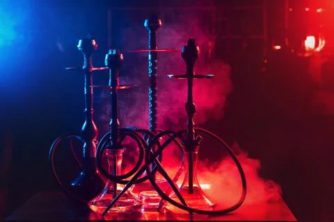 Hookahs on the table with smoke and red and blue light in the lounge cafe Stock Photos