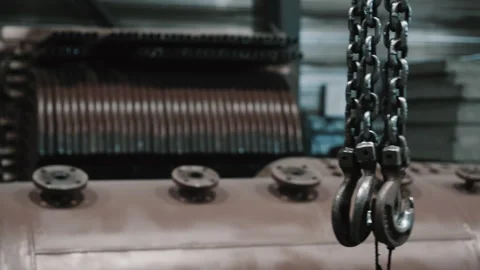 Hooks on chains from a lifting mechanism hang at metalworking plant. Stock Footage 313104054