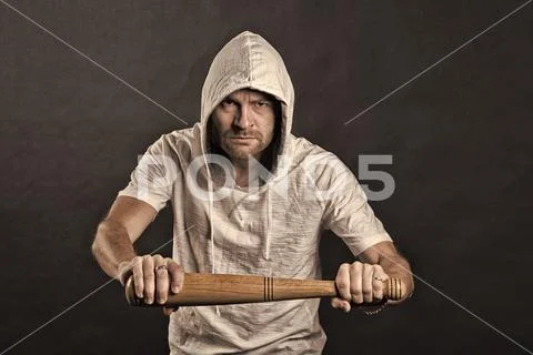 Hooligan hold baseball bat. Bearded man wear hood in hoodie tshirt. Gangster guy Stock Photos