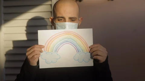 Hope concept: young man at sunset with virus mask and rainbow drawing is sad Stock Footage 129272231