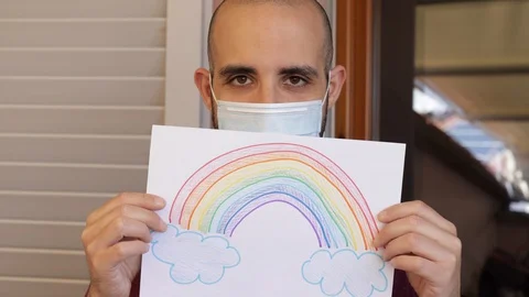 Hope concept: young man with virus mask and rainbow drawing is sad, then smiles Stock Footage 128953330