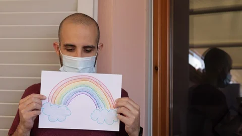 Hope concept: young man with virus mask and rainbow drawing is sad Stock Footage 128953397
