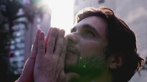 Hopeful and devout young man with closed eyes and clasped hands looks up to.. Stock Footage 254916796