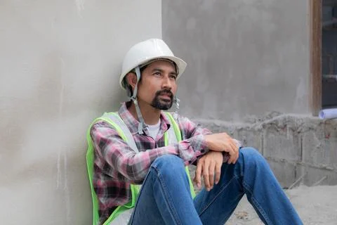 Hopeless builder worker sitting in construction site meet financial crisis,.. Stock Photos