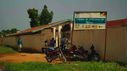 "HÔPITAL DE RÉFÉRENCE DE BETOU" sign with motorcycles below Vidéo 338167540