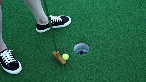 Horizontal 4K close-up video of a mini golf ball being putted into a hole Stock Footage 342078446