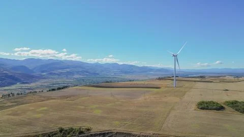 Horizontal aerial drone view of a single modern wind turbine standing in a .. Foto stock