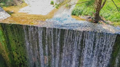Horizontal aerial high angle view of a small concrete river dam with a casc.. Stock Photos