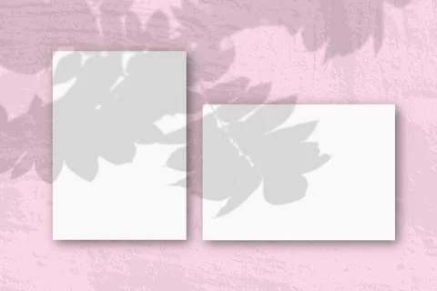 Horizontal and vertical sheets of white textured paper against a pink wall ba Stock Photos