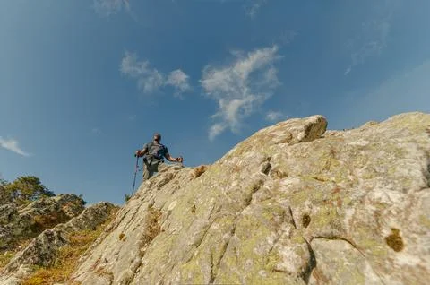Horizontal angle from below looking up at black hiker with his walking sticks Stock Photos