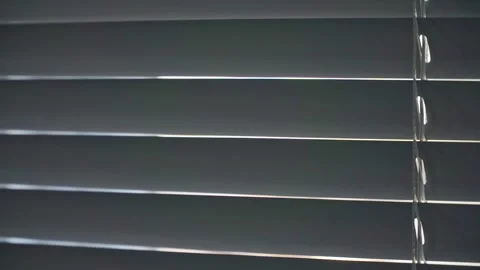 Horizontal blinds swaying over a window, reducing sunlight and enhancing Stock Footage 340858461