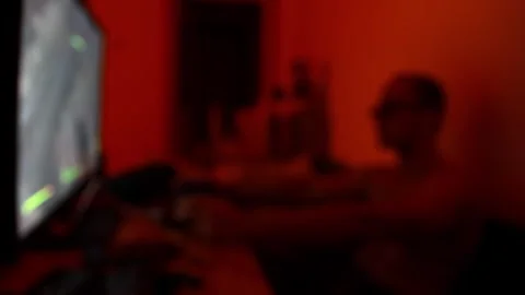 Horizontal blurred shot of a man playing video games at night in a room wit.. 库存影片 346704076