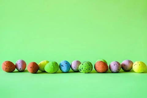 Horizontal border of colorful Easter eggs over green Stock Photos