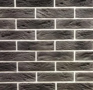 Horizontal brickwork is dark gray with damage. Black background.  Stock Photos
