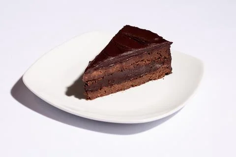 Horizontal chocolate cake slice on white tablecloth with hard shadow Stock Photos