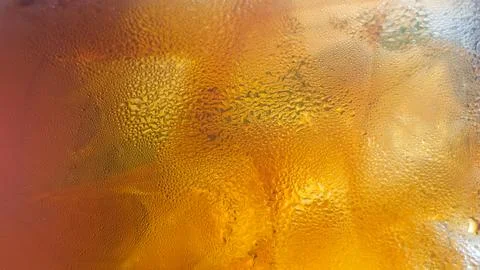 Horizontal close-up of a cold refreshing amber beverage glass covered with .. 스톡 사진