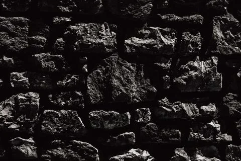 Horizontal close up of a dark black stone wall texture with rough uneven br.. Stock Photos