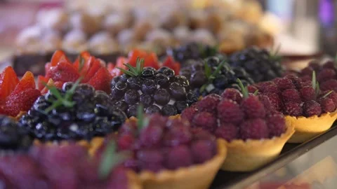 Horizontal close up of fresh berry mini tarts with cream filling in bakery Stock Footage 141605698