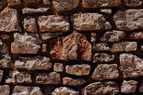 Horizontal close up of an old rustic stone wall texture with brown weathere.. Stock Photos