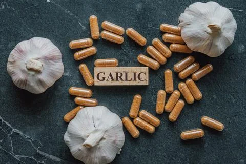 Horizontal close up overhead view of garlic extract capsules surrounding a .. Stock Photos
