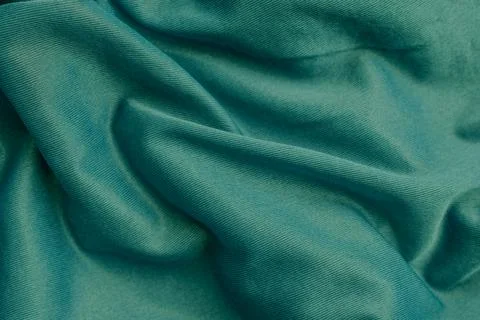 Horizontal close up shot of a smooth dark green or teal silky synthetic fab.. Stock-Fotos