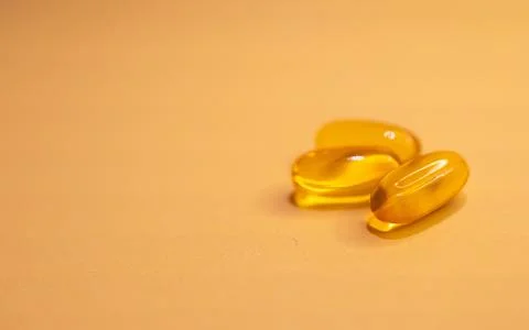 Horizontal close-up of soft capsules of vitamins on amber background. Stock Photos