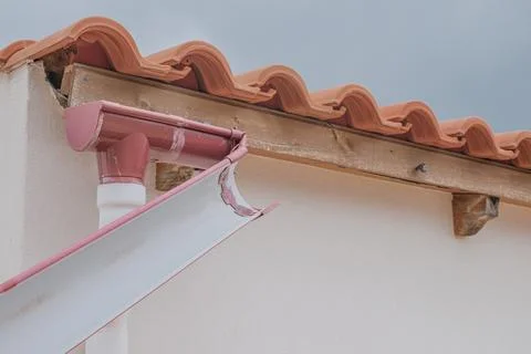 Horizontal close-up view of a broken plastic roof gutter detached and hangi.. Foto stock