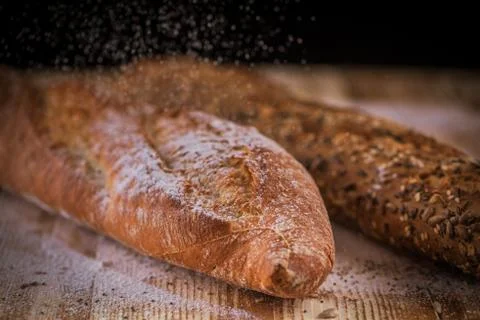 Horizontal closeup view of two fresh crunchy baguettes with raining flour on  Stock Photos