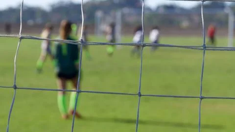 Horizontal composition of a soccer goalie through goal net with shallow depth. Stock Photos