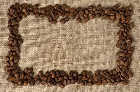 Horizontal frame made from aromatic coffee beans on sacking fabric background Stock Photos