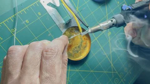 Horizontal high angle view of a technician hands using a cordless gas solde.. Stock Photos